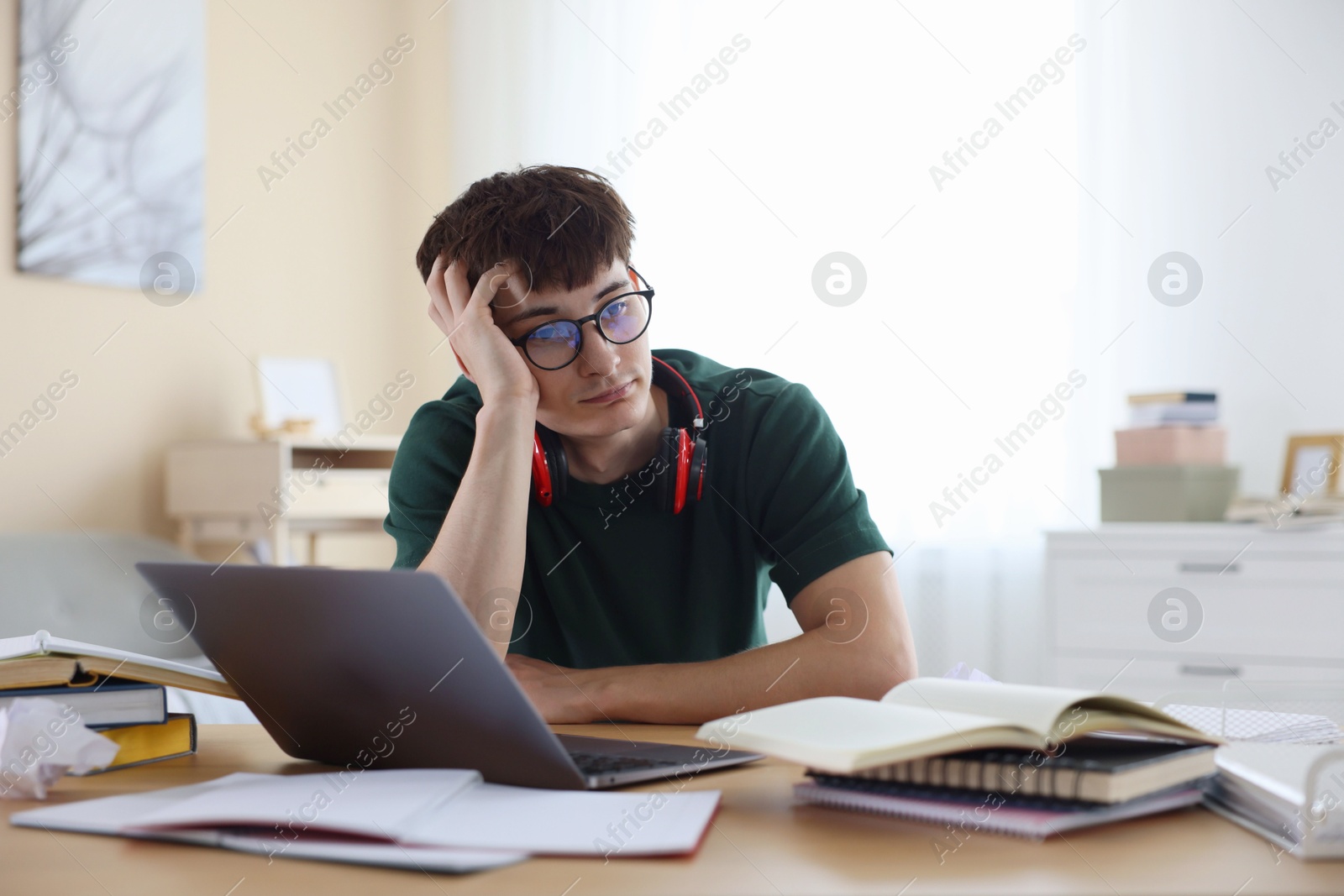 Tired student preparing for exam at table indoors Photo of Tired student preparing for exam at table indoors
