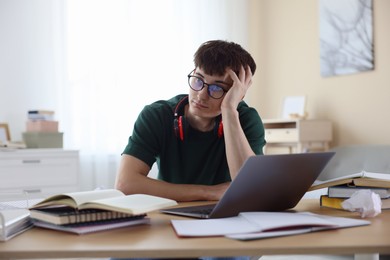 Photo of Tired student preparing for exam at table indoors