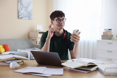 Photo of Worried student crossing fingers for good exam result at table indoors