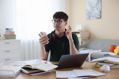 Photo of Worried student crossing fingers for good exam result at table indoors