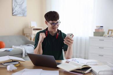 Photo of Happy student celebrating good exam result at table indoors