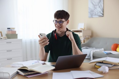 Photo of Happy student celebrating good exam result at table indoors