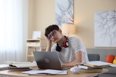 Photo of Worried student preparing for exam at table indoors