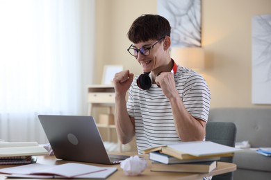 Photo of Happy student celebrating good exam result at table indoors