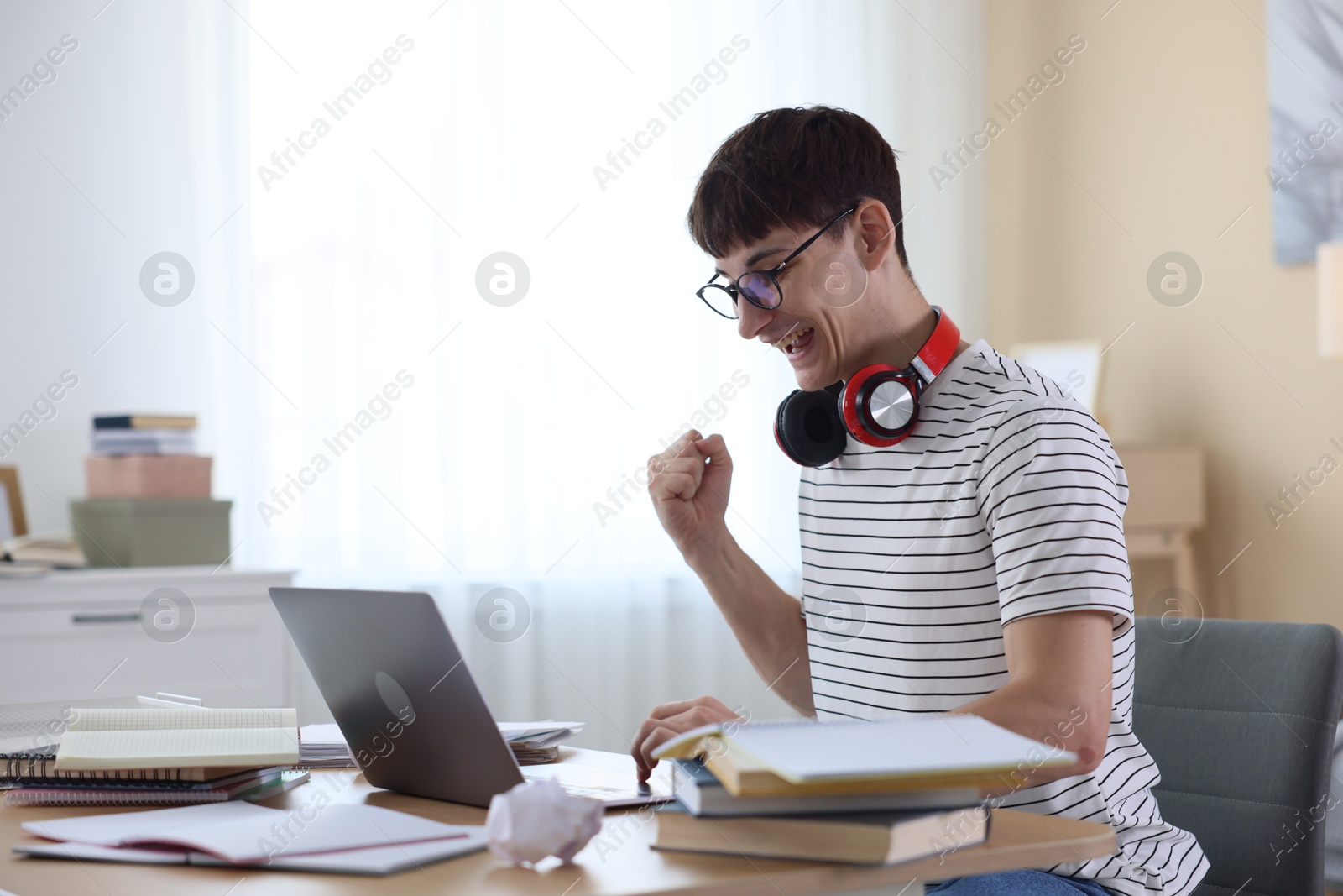 Happy student celebrating good exam result at table indoors Photo of Happy student celebrating good exam result at table indoors