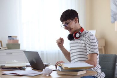 Photo of Happy student celebrating good exam result at table indoors