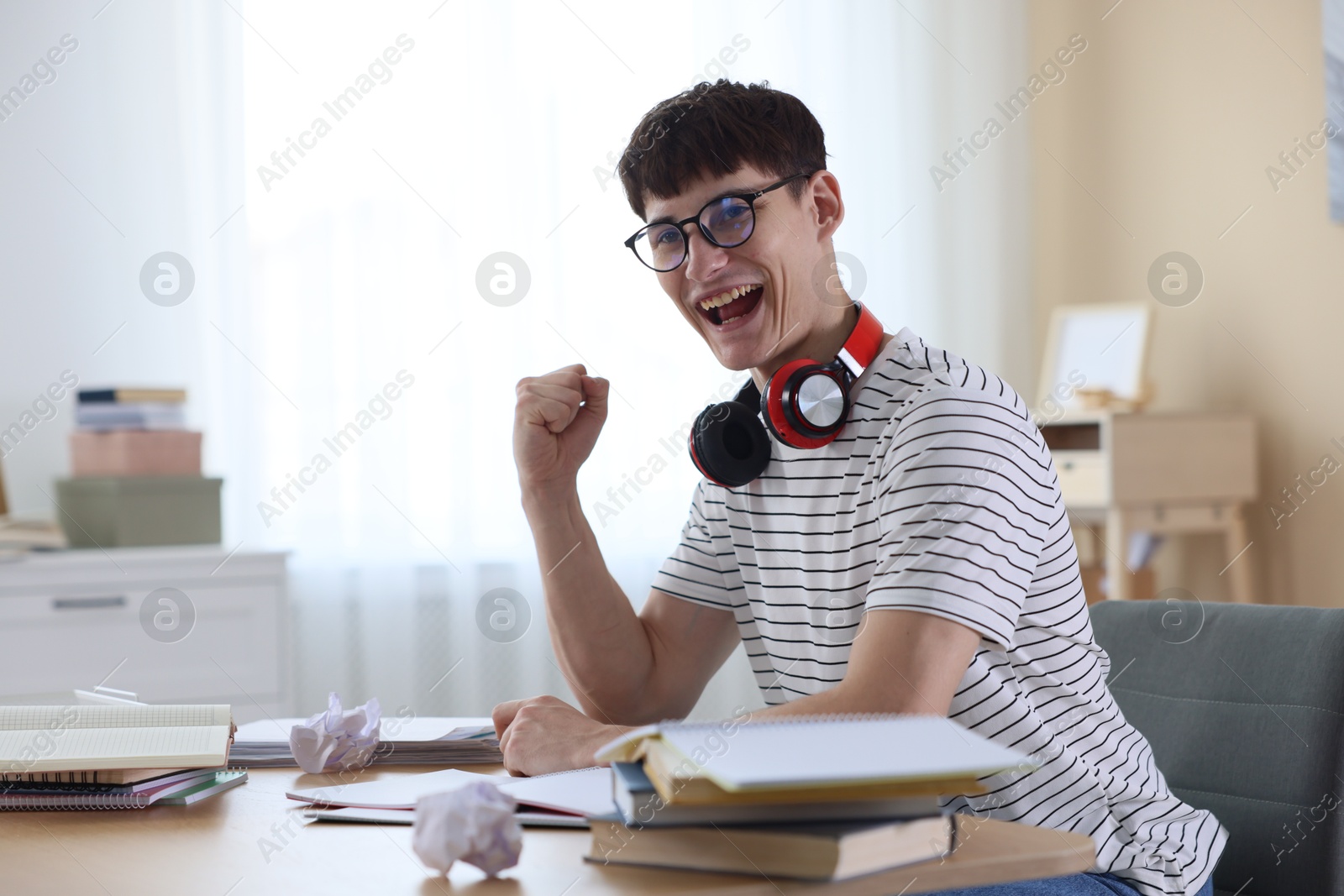 Happy student celebrating good exam result at table indoors Photo of Happy student celebrating good exam result at table indoors