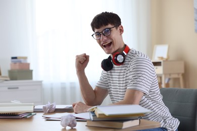 Photo of Happy student celebrating good exam result at table indoors