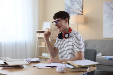 Photo of Happy student celebrating good exam result at table indoors