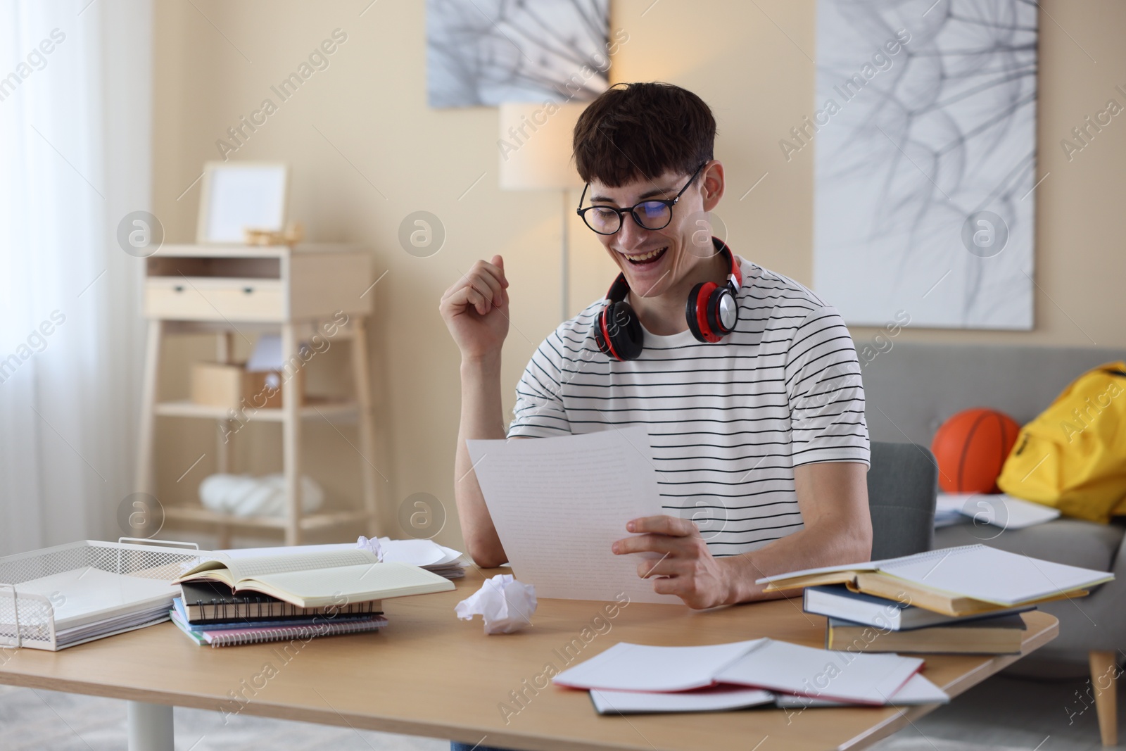 Happy student celebrating good exam result at table indoors Photo of Happy student celebrating good exam result at table indoors