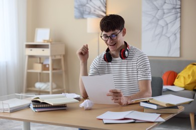 Photo of Happy student celebrating good exam result at table indoors