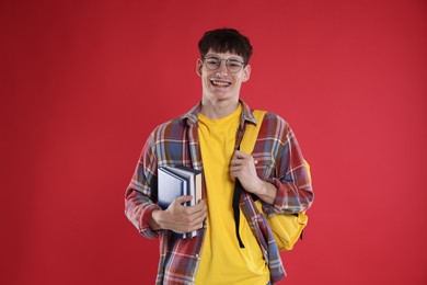 Photo of Good exam result. Happy student with books on red background