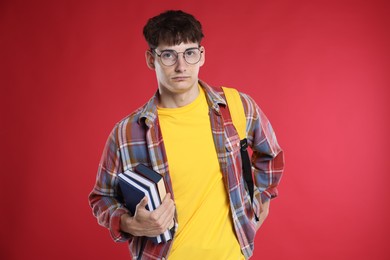 Photo of Student with books worried about his exam result on red background
