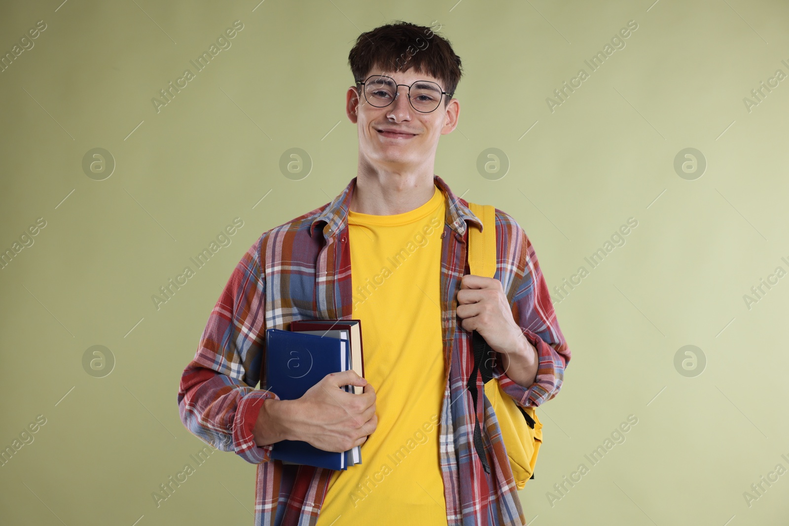 Good exam result. Happy student with books on light olive background Photo of Good exam result. Happy student with books on light olive background