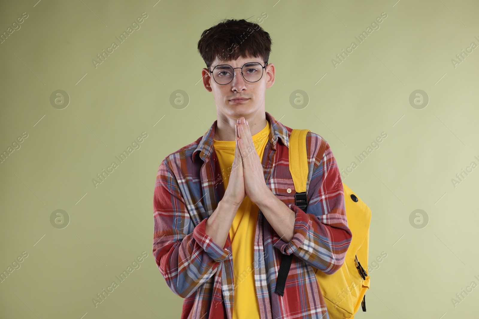 Student with clasped hands praying for good exam result on light olive background Photo of Student with clasped hands praying for good exam result on light olive background