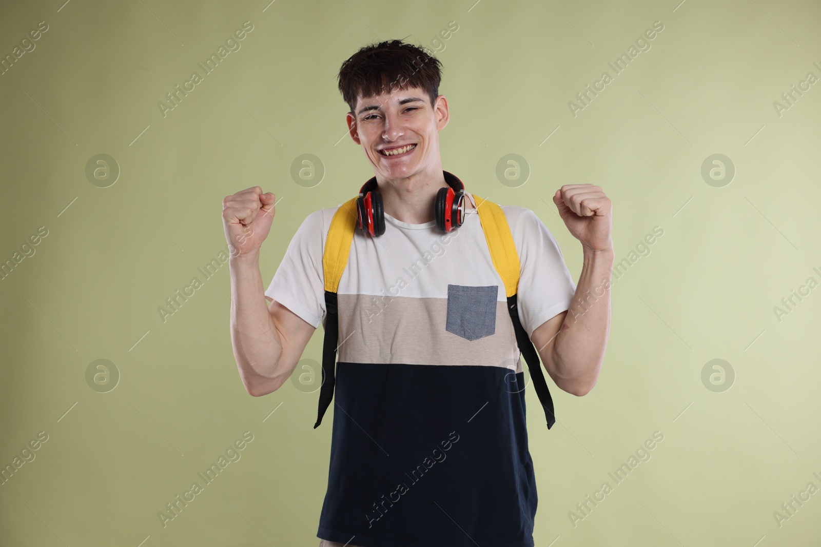 Happy student celebrating good exam result on light olive background Photo of Happy student celebrating good exam result on light olive background
