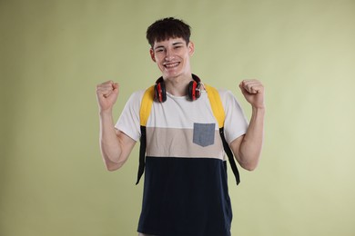Photo of Happy student celebrating good exam result on light olive background