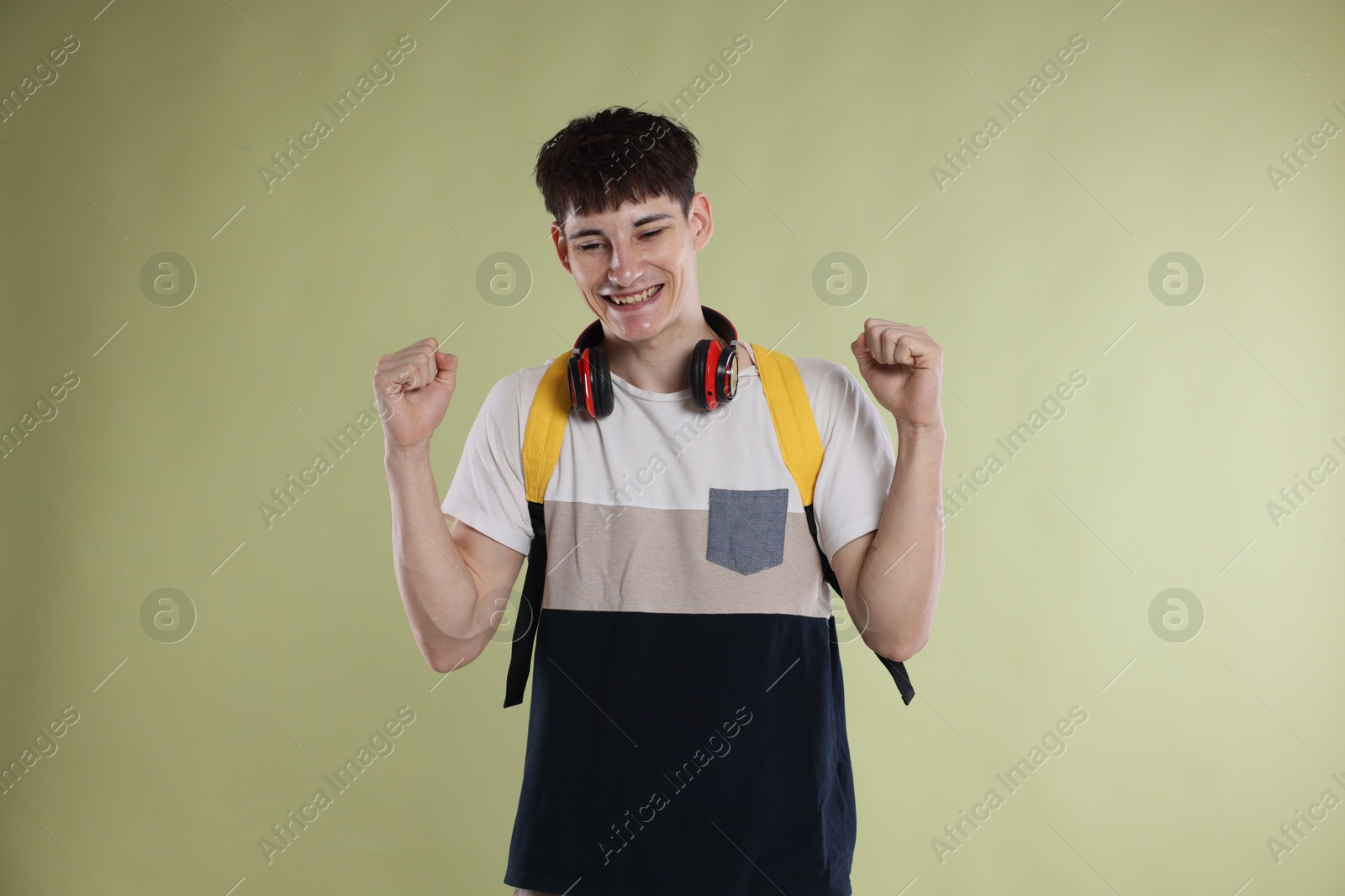 Happy student celebrating good exam result on light olive background Photo of Happy student celebrating good exam result on light olive background