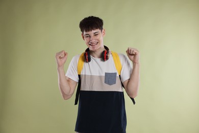 Photo of Happy student celebrating good exam result on light olive background