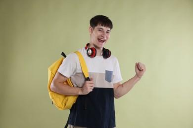 Photo of Happy student celebrating good exam result on light olive background
