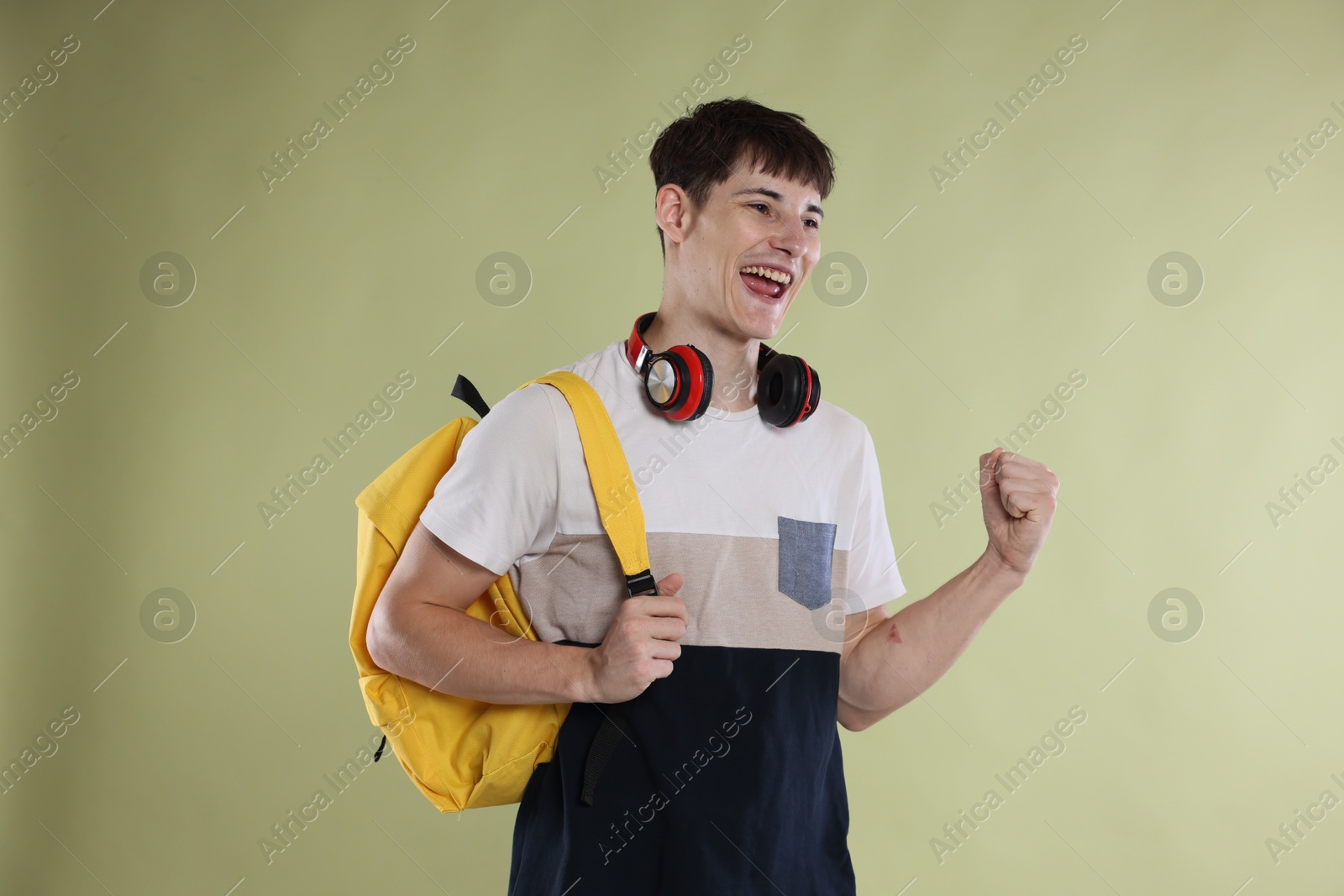 Happy student celebrating good exam result on light olive background Photo of Happy student celebrating good exam result on light olive background