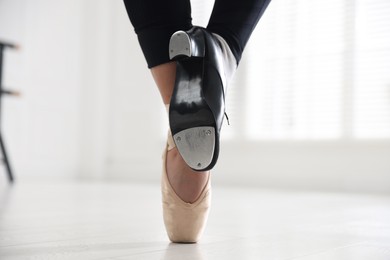 Photo of Teenage girl in tap and pointe shoe indoors, closeup