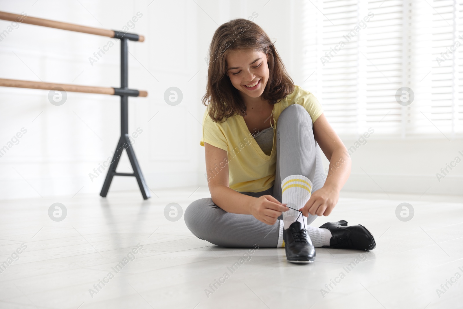 Teenage girl tying shoelace of tap shoe indoors Photo of Teenage girl tying shoelace of tap shoe indoors