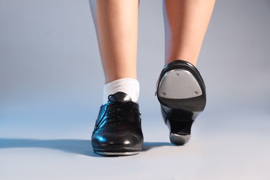 Photo of Teenage girl in tap shoes on light background, closeup