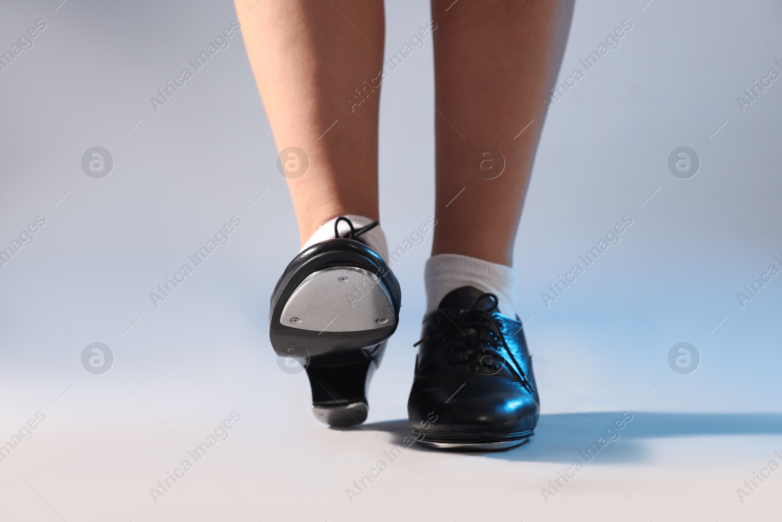 Photo of Teenage girl in tap shoes on light background, closeup