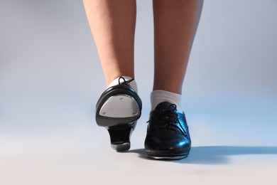 Photo of Teenage girl in tap shoes on light background, closeup