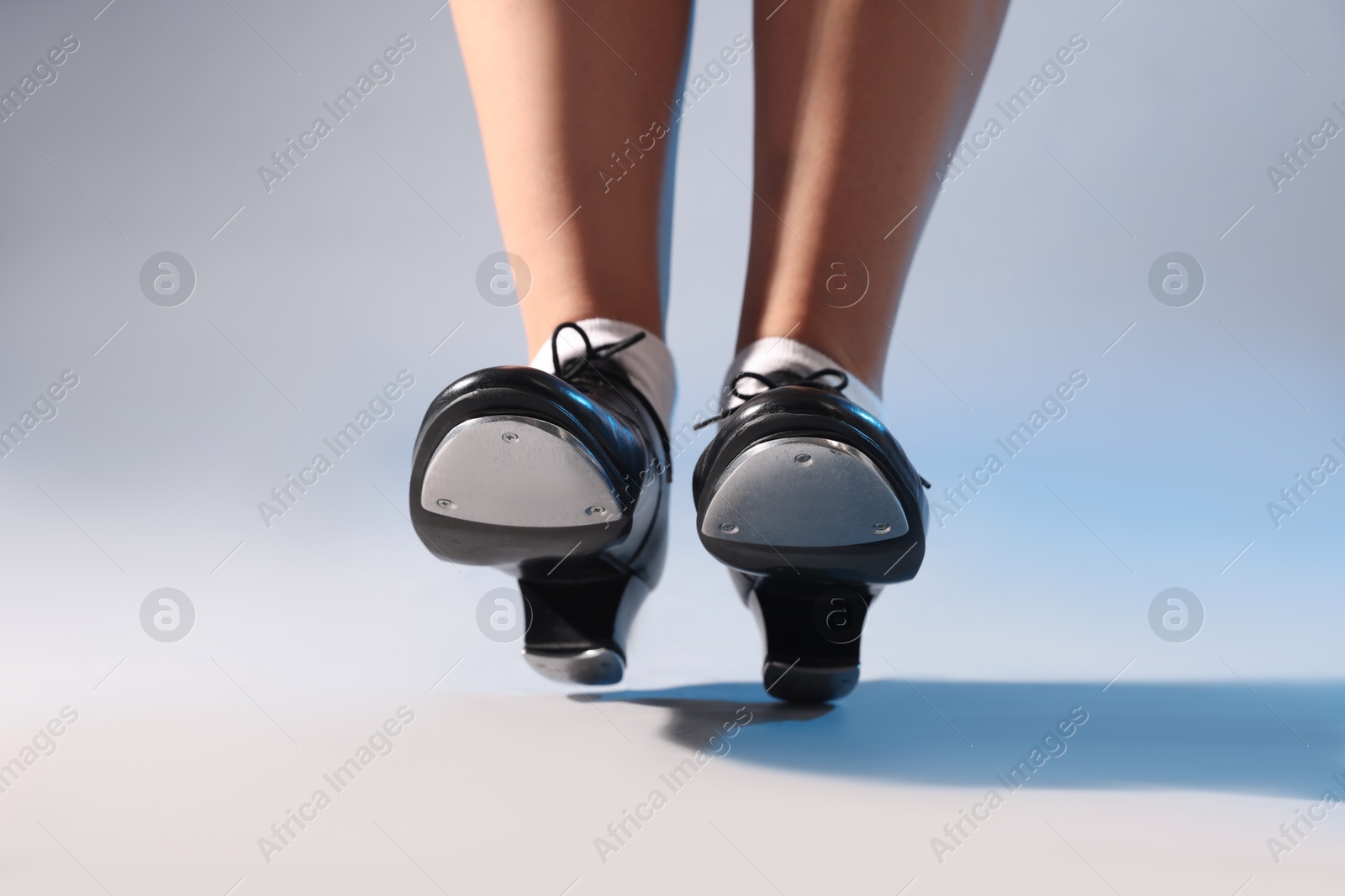 Photo of Teenage girl in tap shoes on light background, closeup