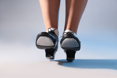 Photo of Teenage girl in tap shoes on light background, closeup