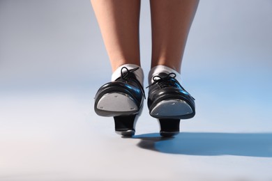 Photo of Teenage girl in tap shoes on light background, closeup