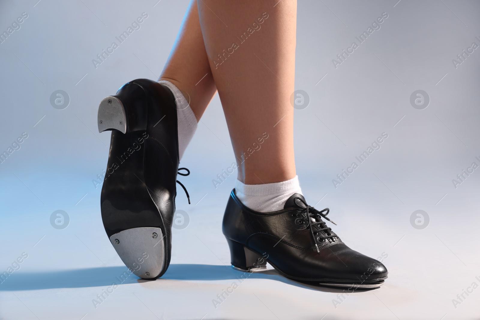 Photo of Teenage girl in tap shoes on light background, closeup
