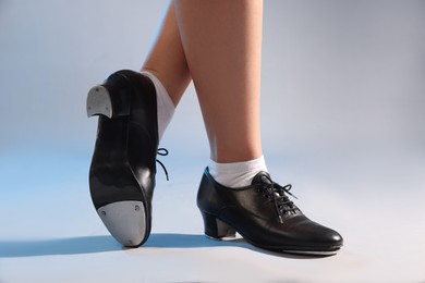 Photo of Teenage girl in tap shoes on light background, closeup
