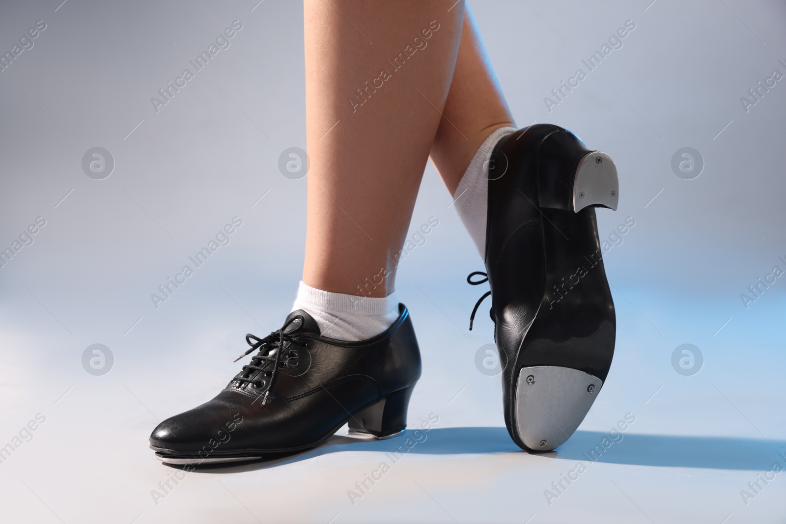 Photo of Teenage girl in tap shoes on light background, closeup