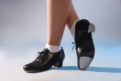 Photo of Teenage girl in tap shoes on light background, closeup