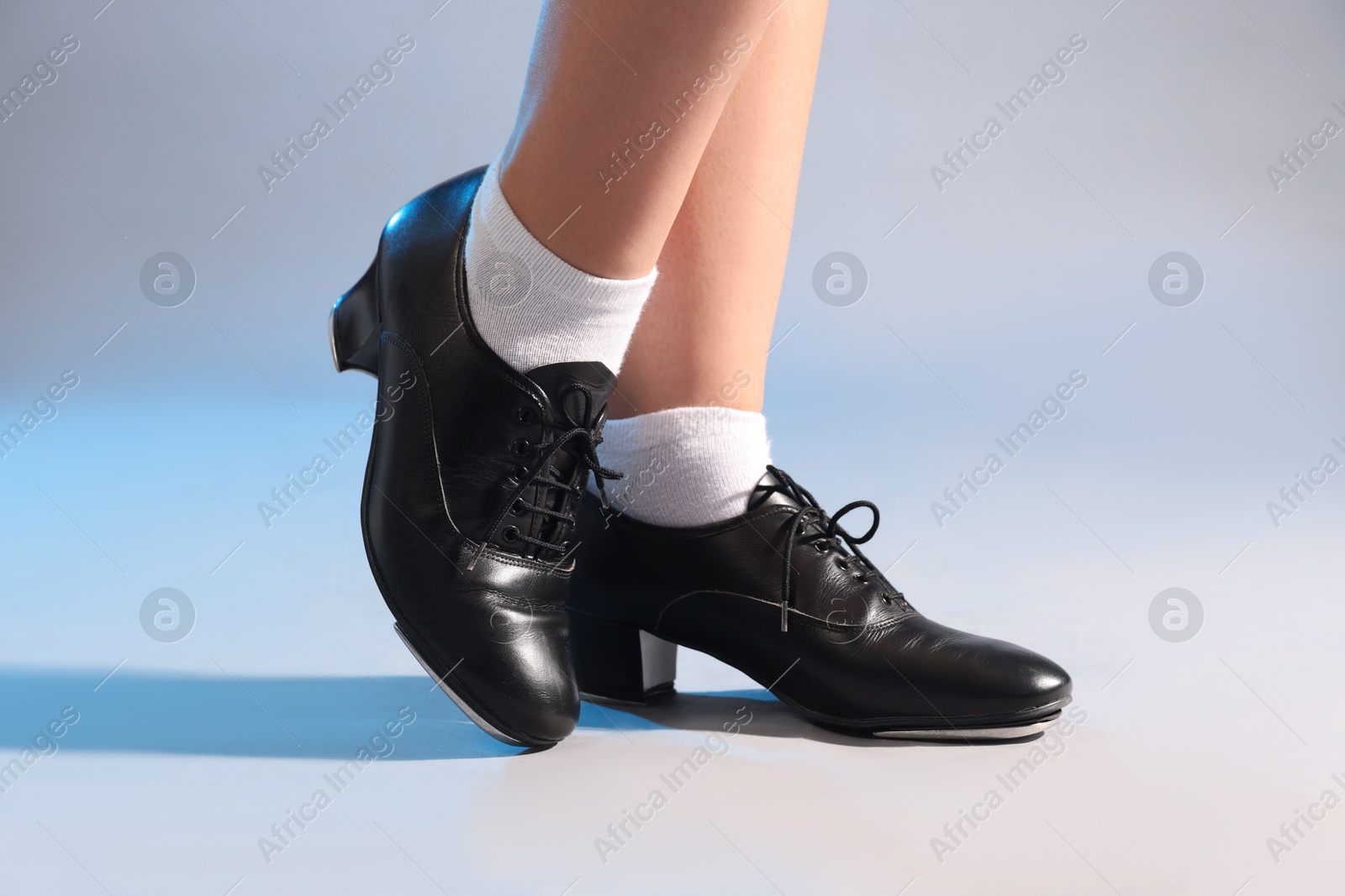 Photo of Teenage girl in tap shoes on light background, closeup
