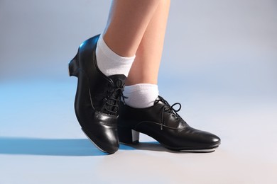 Photo of Teenage girl in tap shoes on light background, closeup
