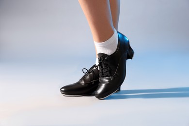Photo of Teenage girl in tap shoes on light background, closeup