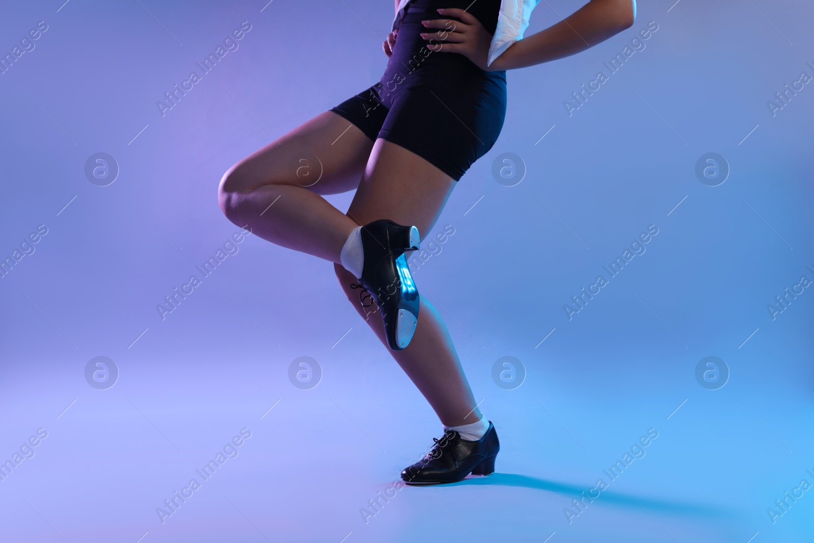 Photo of Teenage girl in tap shoes dancing on color background, closeup