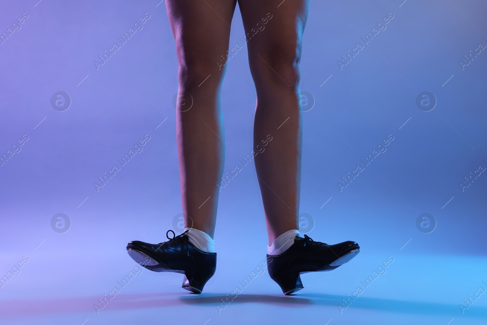 Photo of Teenage girl in tap shoes dancing on color background, closeup