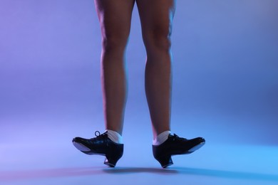 Photo of Teenage girl in tap shoes dancing on color background, closeup