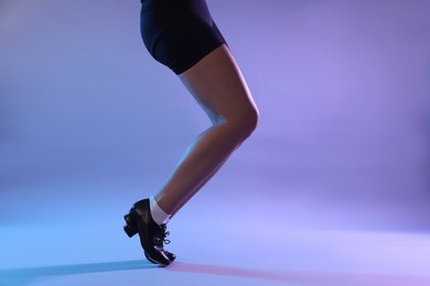 Photo of Teenage girl in tap shoes dancing on color background, closeup