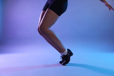 Photo of Teenage girl in tap shoes dancing on color background, closeup