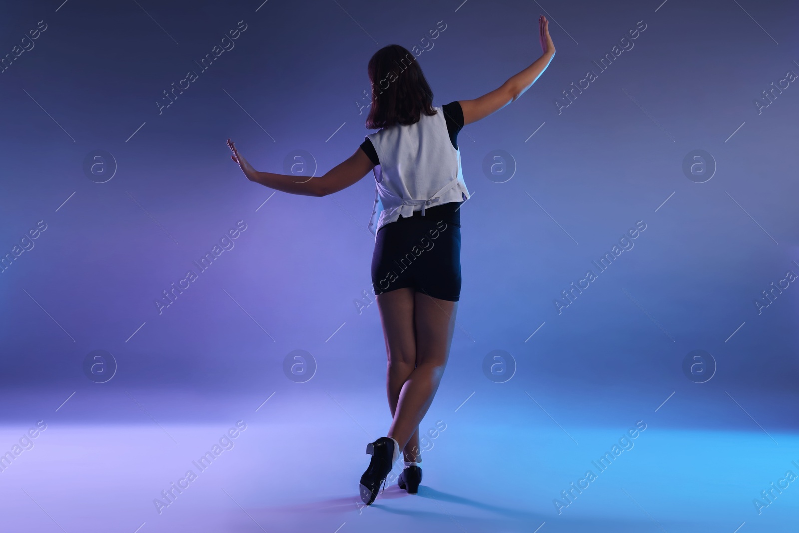 Photo of Teenage girl in tap shoes dancing on color background, back view