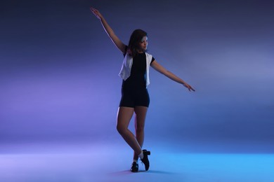 Photo of Teenage girl in tap shoes dancing on color background