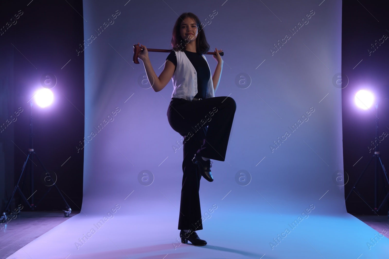 Teenage girl in tap shoes with cane dancing on color background Photo of Teenage girl in tap shoes with cane dancing on color background