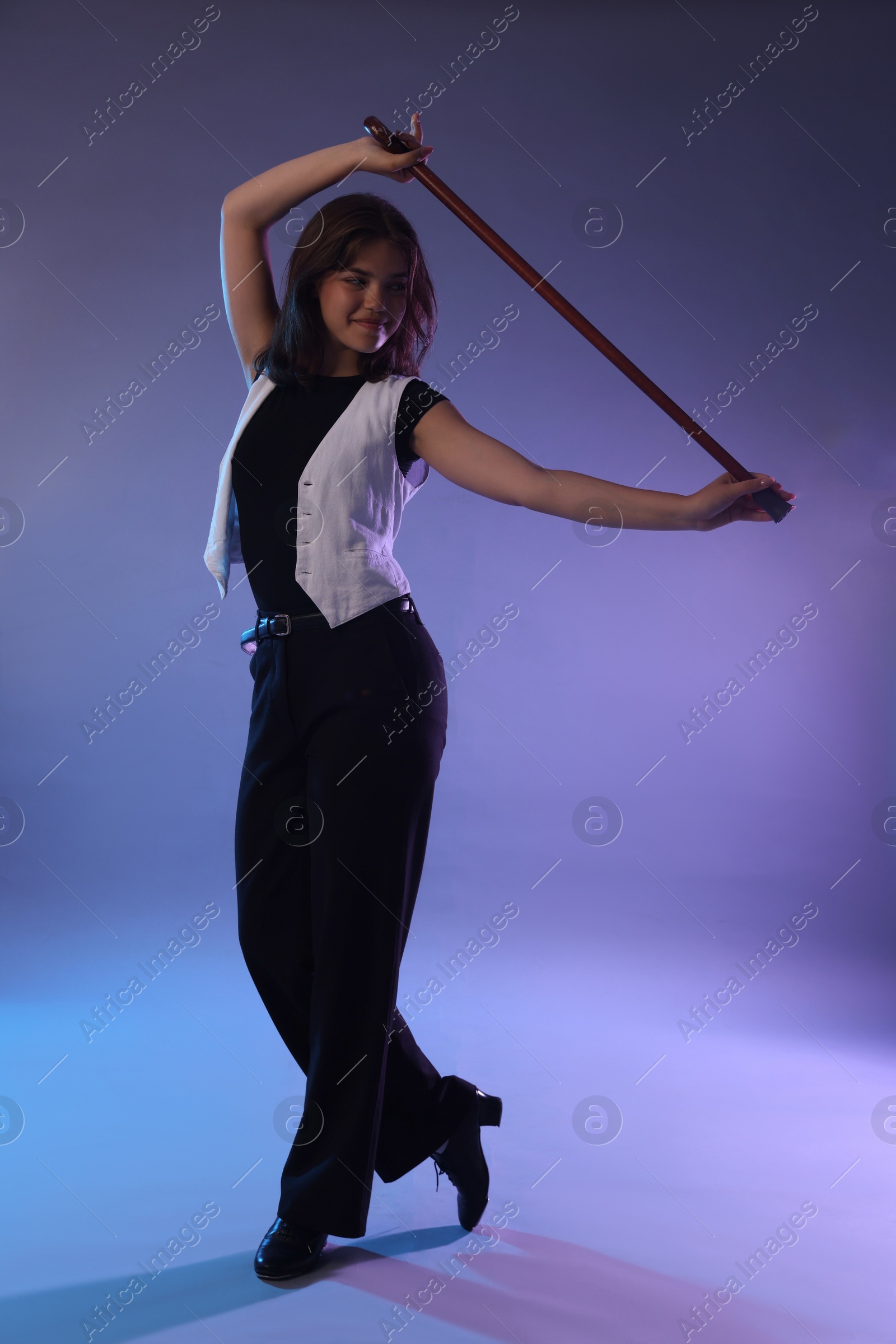 Teenage girl in tap shoes with cane dancing on color background Photo of Teenage girl in tap shoes with cane dancing on color background