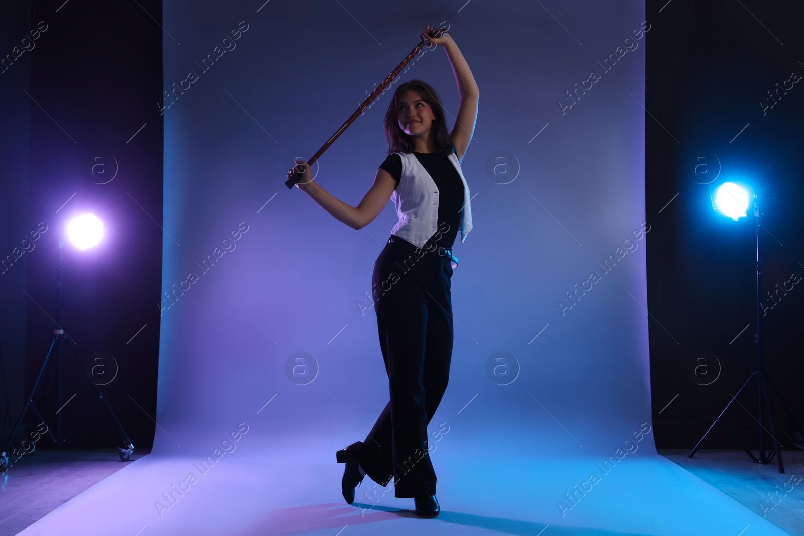 Teenage girl in tap shoes with cane dancing on color background Photo of Teenage girl in tap shoes with cane dancing on color background